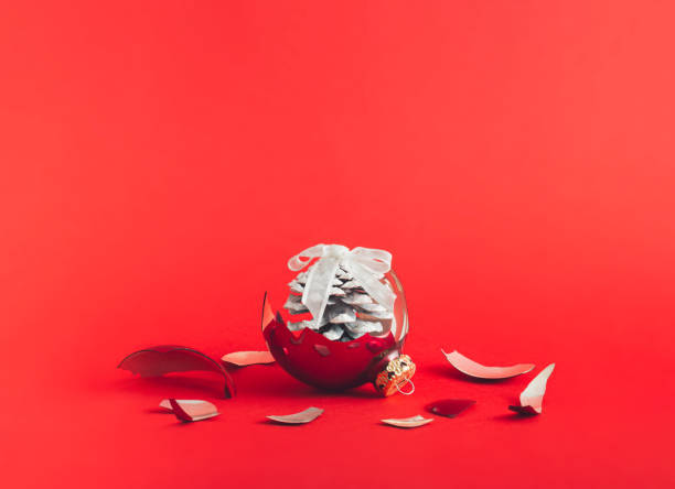 istock Creative idea made of broken red bauble scattered at pieces and white colored pine core against red background. Minimal christmas concept. Nature against artificial. 1451122774