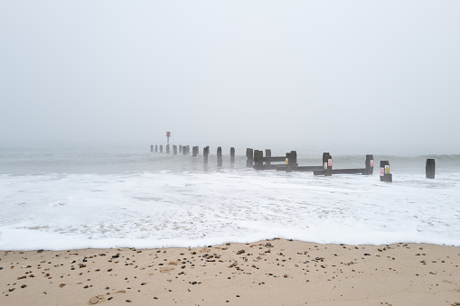 Foggy and cold morning on a North Sea beach in the east of England. Sea fog can be seen coming in from the sea.
