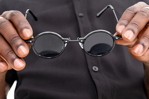 African-American black man holding sunglasses.