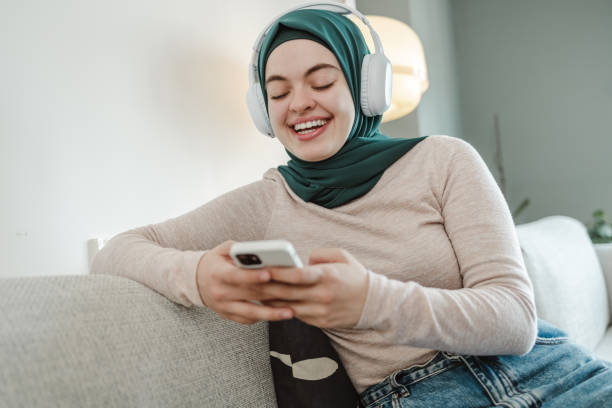 istock Smiling young woman using a smart phone at home 1451130856