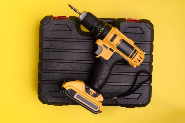 istock Electric cordless yellow drill driver and an empty black carrying case on a yellow background. 1451130868