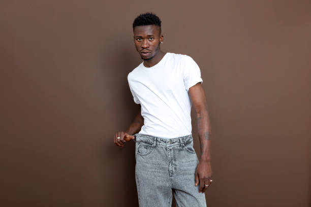 istock African descent black man posing awkwardly in front of brown wall looking at camera. 1451132995