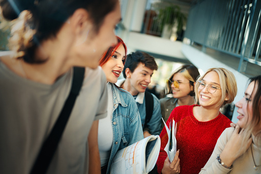 Closeup side view of a group of high school students on a break in a hallway laughing.