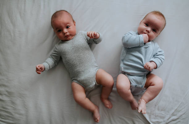 Twin babies are lying on the bed