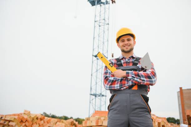 istock construction mason worker bricklayer installing red brick with trowel putty knife outdoors. 1451138407