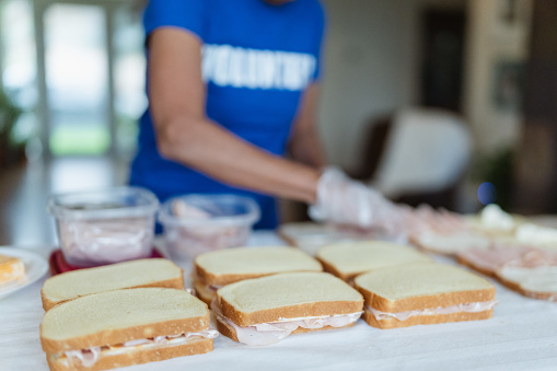 Cropped shot of sandwiches on a table being prepared for charity and relief by a group of unidentifiable volunteers. Homeless shelter, humanitarian aid, and community outreach concepts.