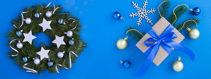 Christmas decor. Christmas gift box with tied blue bow and ring or wreath on the blue background.