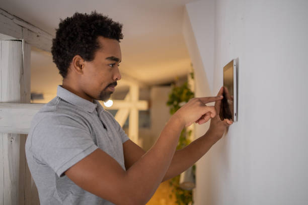 istock Young man adjusts the temperature at home with a device on the wall 1451150999