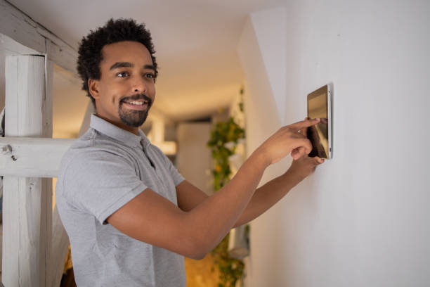 istock Young man adjusts the temperature at home with a device on the wall 1451151002