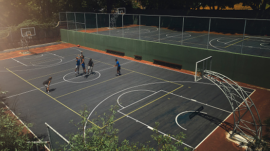 Basketball, outdoor court and athlete men showing energy in ball sports competition or game for fitness and training. Above view, exercise and sport with community people playing streetball together