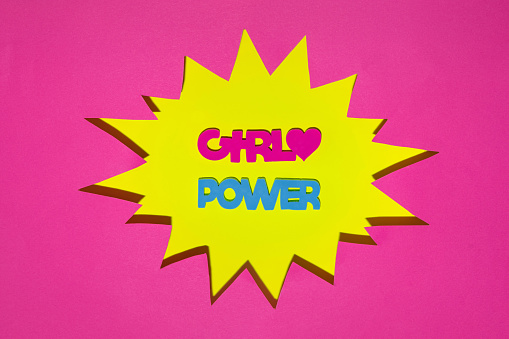 Creative pop art Women's Day idea. Girl power letters in yellow comic speech bubble. Modern March 8 concept. Minimal feminist flat lay composition.