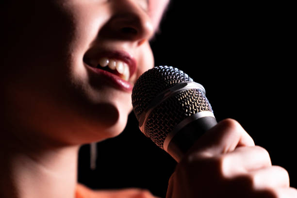 istock young woman singing into microphone 1451152884