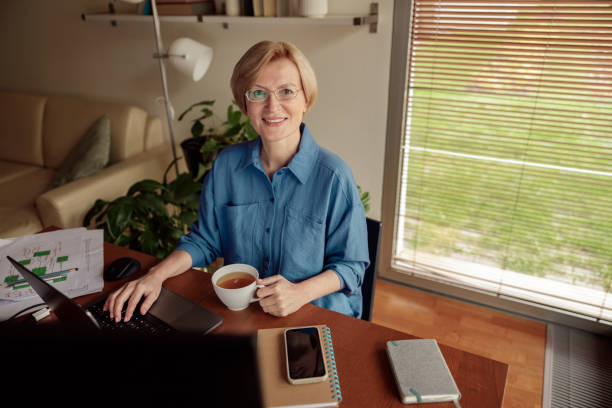 istock Mature businesswoman drinking tea during working day from home office. Freelance work concept 1451155366