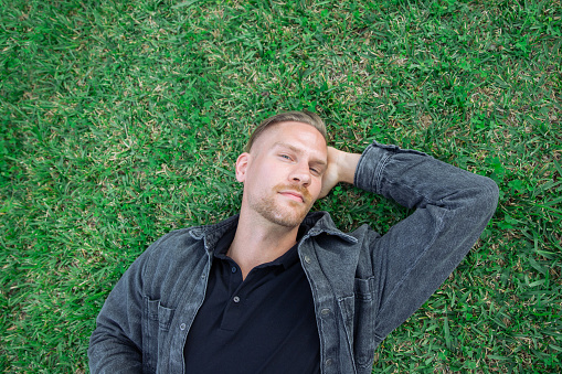 Portrait of a Caucasian man lying on a grass lawn, photo from above