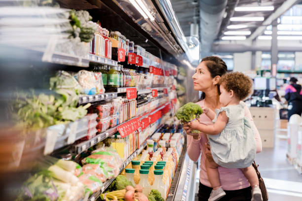 istock Baby in mom's arms plays with broccoli while shopping 1451157675