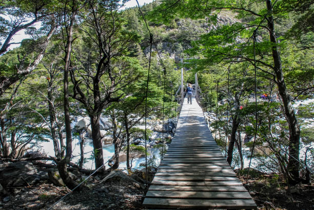 Torres Paine N.P, W Circuit, Chile - nov 10, 2006: a hiker cross a small wooden suspension bridge crosses the stream that descends from the Valle dei Francesi into the Paine group, Paine N.P.