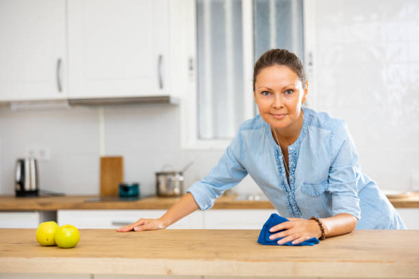 mujer enfocada limpiando la mesa de la cocina en casa - cleaning domestic kitchen counter top housework fotografías e imágenes de stock
