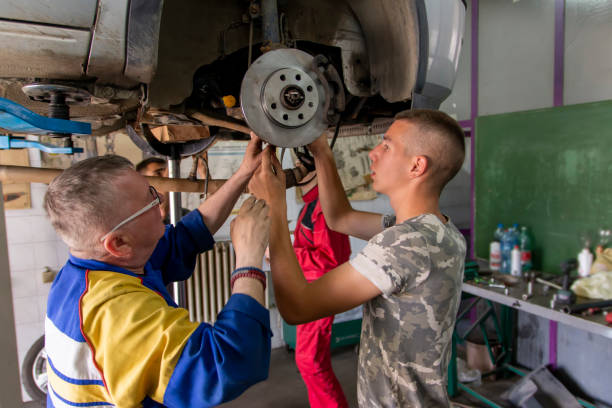 istock Male tutor with students on auto mechanic apprenticeship course at college 1451158104