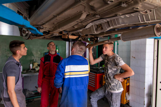 istock Male tutor with students on auto mechanic apprenticeship course at college 1451158115