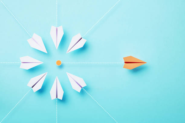 istock Paper Planes Moving Towards An Orange Point On Blue Background 1451180787