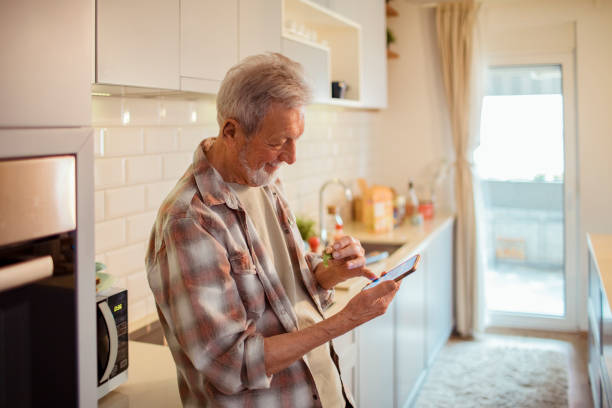 istock Senior man having a sandwich while checking his phone 1451180809