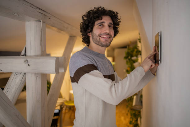 istock Young man adjusts the temperature at home with a device on the wall 1451181208