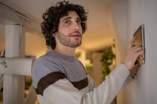 istock Young man adjusts the temperature at home with a device on the wall 1451181256