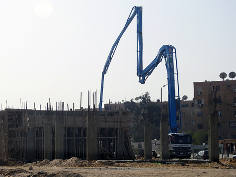 Cairo, Egypt, December 12 2022: A truck-mounted concrete boom pump at the side of the road pouring concrete to new building, selective focus of concrete truck at the construction site of new building, selective focus