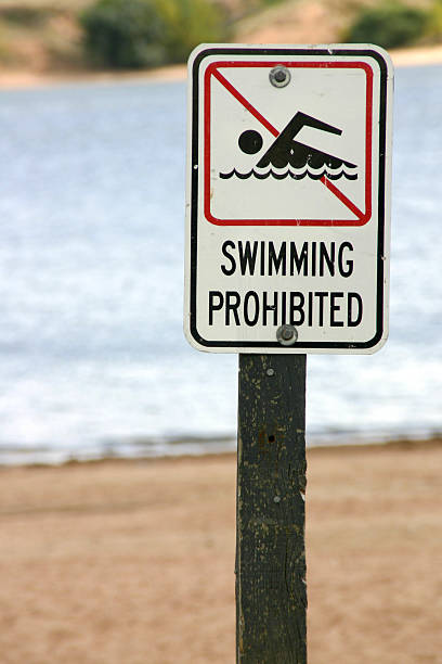 "Swimming Prohibited" sign post - Vertical stock photo