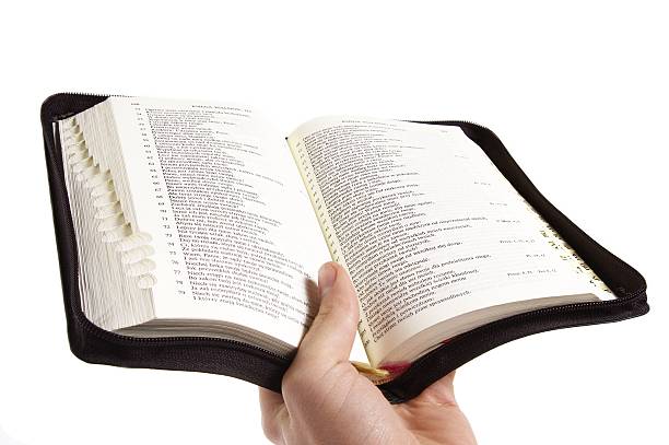 opened bible held in the hand stock photo