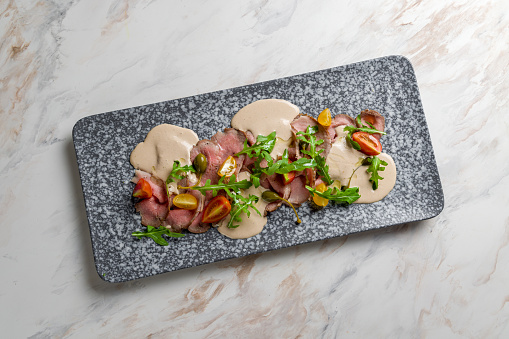 vitello tonato, roastbeef with tuna sauce on a plate on white marble table top view