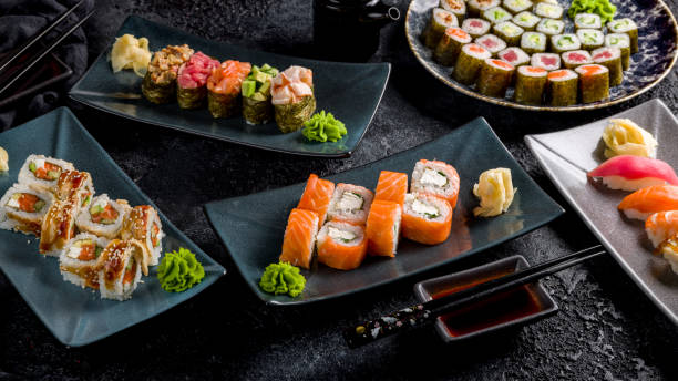 istock Philadelphia roll with salmon, roll canada with eel and salmon, maki rolls, sushi gunkans, sushi with salmon, tuna on dark stone table 1451203450
