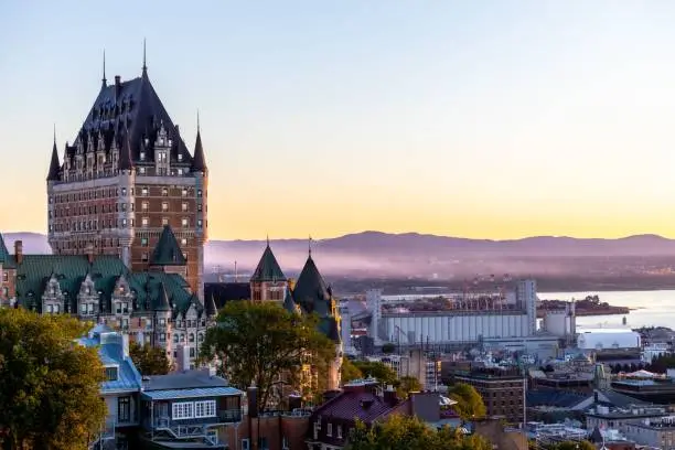 A beautiful view of the Chateau Frontenac surrounded by greenery in Quebec, Canada at sunrise