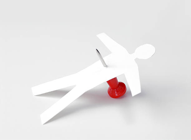 Paper cut out man stabbed with a map pin like a voodoo doll Office politics. Paper doll stabbed with red push pin. Abstract concept of fallen businessman.  revenge stock pictures, royalty-free photos & images