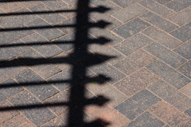 Pattern from a metal fence on a pathway on a sunny day.