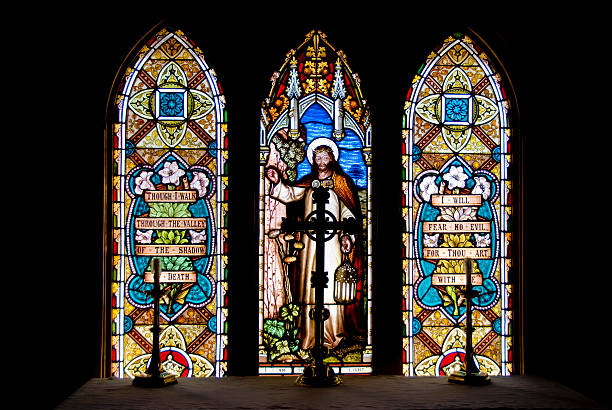 Communion Table in front of Stained Glass Table with crucifix and candles in front of three panel stained glass window. Stained glass is a depiction of Jesus after the resurrection showing nail scarred hand and crown of thorns. Photo was taken at Christ Anglican Church near Millarville, Canada. Window was installed in the historic vertical log building in 1901 and is a copy of Holman Hunt's ""Light of the World"". The original is at Keble College, Oxford. anglican eucharist stock pictures, royalty-free photos & images