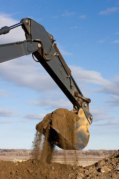 istock Excavator arm and scoop digging dirt at road construction 145121912