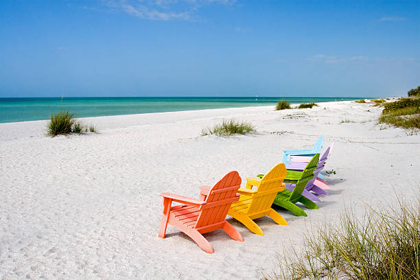 Six multi color chairs set on an empty beach toward the sea  Adirondack chairs on a resort island beach sanibel island stock pictures, royalty-free photos & images