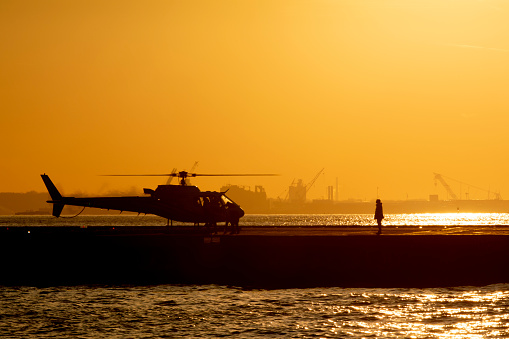 Ramp agent on tarmac at heliport during sunset