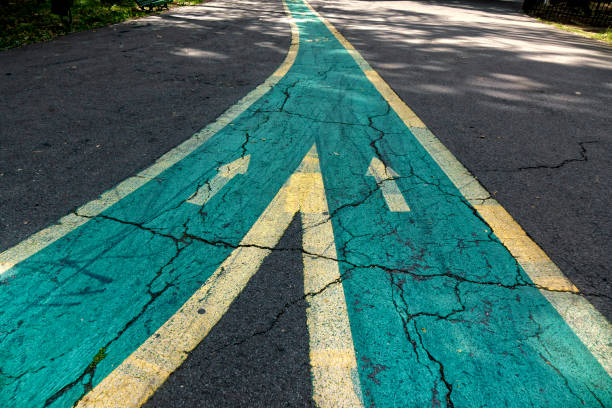 fusion des panneaux fléchés sur une route asphaltée - fusionner photos et images de collection