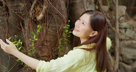 Asian woman embraces in nature by hugging tree feeling comfortablely