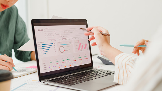 Closeup group of Asian business people meeting discuss project plan and financial results in office. Marketing strategy analysis, stock market trading, financial consultant concept.