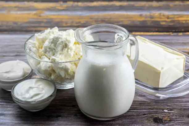Fresh dairy products, milk, cottage cheese, yogurt, sour cream and butter on a wooden background.
