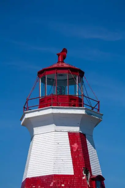 A vertical shot of the Head Harbour Lightstation on a blue sky background in Campobello, New Brunswick