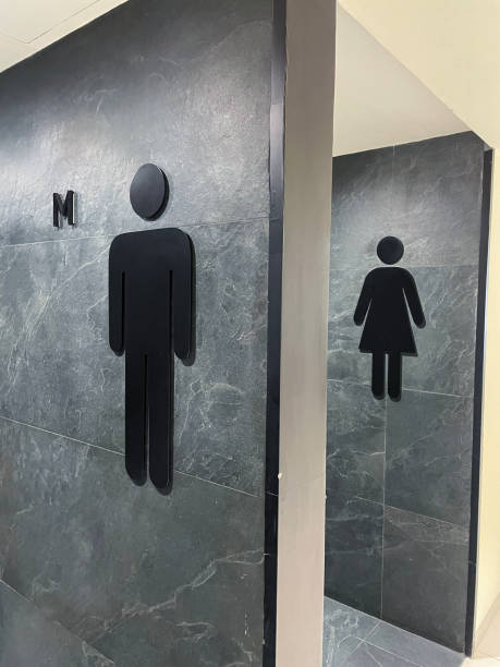 Image of modern public toilet wall signs, black, men (gents) and women (ladies) symbols on grey, marble effect tiled public toilet wall Stock photo showing signs outside of some public toilets, indicating the facilities available. mens room stock pictures, royalty-free photos & images
