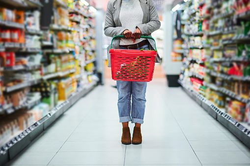 Woman, grocery supermarket and basket in hands for food produce, retail and commercial goods. Customer in supermarket, shopping in convenience store and buying products for special, discount or sale