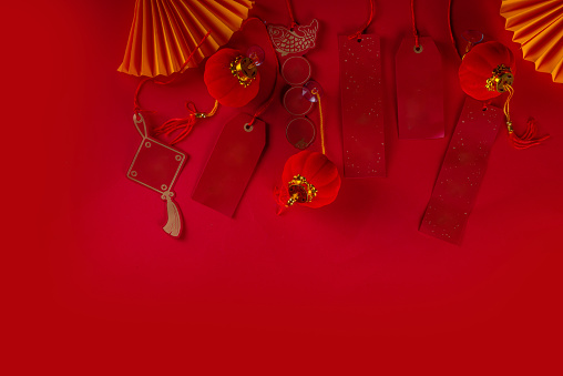 Chinese new year background, with festive Chinese lanterns, paper fans and traditional New Year stripes posters for wishes on bright red background copy space