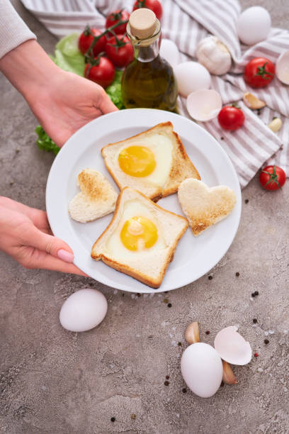 istock Woman pits plate with Fried Egg on Toast Bread on concrete table for Breakfast 1451281587