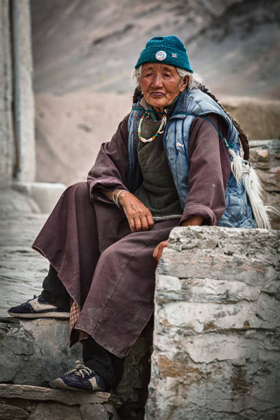 Old woman holding hand prayer wheel and prayer beads