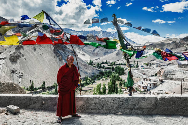 monje budista parado afuera con banderas de oración lugta en lamayuru gompa - tibetan buddhism fotos fotografías e imágenes de stock
